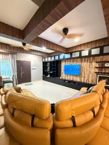 a living room with two leather chairs and a flat screen tv at Walnut Grove Premium Pool Villa in Batu Caves
