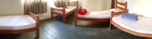 a room with three beds and a chair in it at Hotel Kairós in Campinas