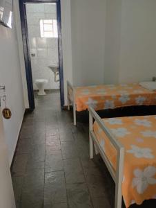 a room with two beds and a bathroom with a toilet at Hotel Kairós in Campinas +2 photos