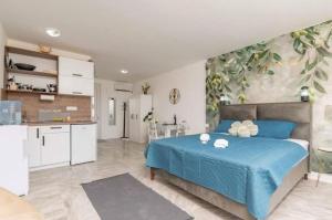 a bedroom with a blue bed and a kitchen at Apartmani Olga in Stari Bar