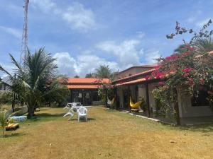 a house with a yard with chairs and flowers at Rancho Capilé Suítes à Beira Mar in Japaratinga +11 photos