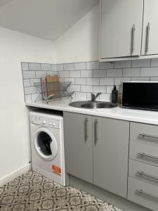 a kitchen with a sink and a washing machine at The Hive 2-Bed Apartment with Kitchen and Private Bathroom in Lively Monton Village - Sleeps 4 - Free WiFi - Parking Nearby in Manchester +39 photos