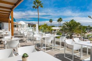 a row of tables and chairs on a patio with palm trees at Elba Premium Suites - Adults Only in Playa Blanca