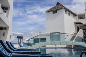 a pool with lounge chairs in front of a building at Best Western Plus Luna del Mar in Manzanillo