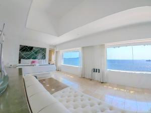 a white living room with a white couch and a large window at Best Western Plus Luna del Mar in Manzanillo