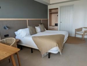 a bedroom with a large bed and a table at Hotel Restaurant Juanito Platja in Sant Carles de la Ràpita