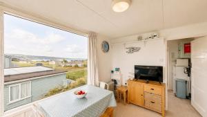 a living room with a table and a large window at F71 Elova, Riviere Towans in Hayle