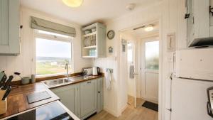a small kitchen with a sink and a refrigerator at F71 Elova, Riviere Towans in Hayle +8 photos