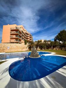 a blue swimming pool with a building in the background at Alcossebre Panorama Suite, Piscina y Terraza con Vistas in Alcossebre