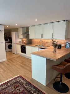 a kitchen with white cabinets and a wooden counter top at Hornbeams Annexe - Deluxe Apartment in Biddenden