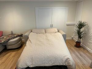 a bedroom with a bed and a couch and a plant at Hornbeams Annexe - Deluxe Apartment in Biddenden
