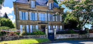 an old house with a fence with garland on it at Maison de Mags & Mags Marie Antoinette Room in Lanouaille