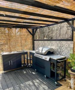 an outdoor kitchen with a grill on a deck at Maison de Mags & Mags Marie Antoinette Room in Lanouaille