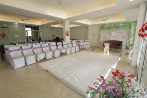 a banquet hall with white chairs and a dance floor at Mangalam Hotel and Restaurant in Lachhmangarh Sīkar