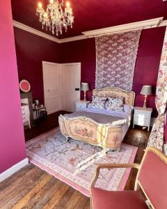 a bedroom with a bed with purple walls and a chandelier at Maison de Mags & Mags Marie Antoinette Room in Lanouaille +11 photos