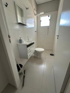 a white bathroom with a toilet and a sink at 04 Studios centro,proximo a rodoviaria-itapeva sp in Itapeva