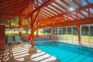 a swimming pool in a pavilion with a wooden roof at Encanto del Rio in Villa La Angostura