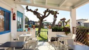 a patio with tables and chairs and a tree at Camping Costa Dorada Bungalow Maia in Canet de Mar