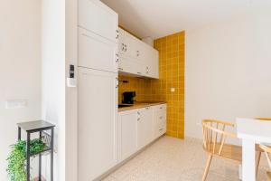 a small kitchen with white cabinets and a table at StoneBridge Riverside Mountain Apartments in Loriga