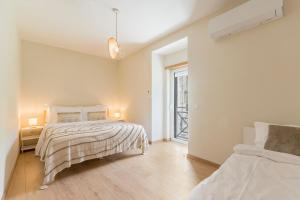 a white bedroom with two beds and a window at StoneBridge Riverside Mountain Apartments in Loriga
