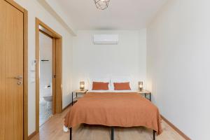 a bedroom with a bed with orange sheets and a toilet at StoneBridge Riverside Mountain Apartments in Loriga +72 photos