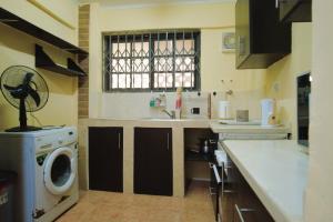 a kitchen with a sink and a washing machine at The Plan Budget Apartment Borteyman Accra in Accra