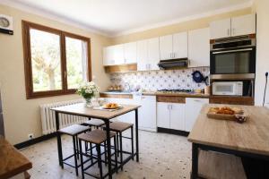 a kitchen with white cabinets and a table and chairs at Maison 10 personnes 4 chambre 2 sdb in Liourdres