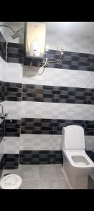 a bathroom with a toilet and a black and white wall at The Royal Lavender in Rānchī