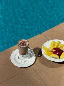 a cup of coffee and a plate of fruit on a table at Hotel Viajante in Landusane