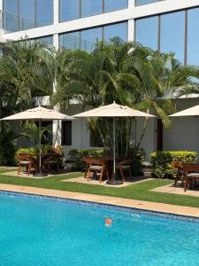 a pool with tables and umbrellas next to a building at Hotel Viajante in Landusane