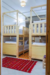 two bunk beds in a room with a rug at The Palm Surfhouse in Tamraght Ouzdar