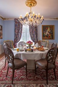 a dining room with a white table with chairs and a chandelier at Maison d'hôtes de charme La Rose de Ducey près du Mont Saint Michel in Ducey