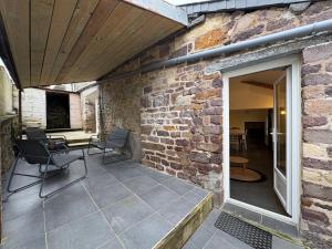 a patio with chairs and a brick wall at Clécy Chouette maison atypique centre in Clécy