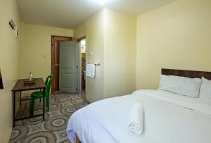 a hotel room with a bed and a desk and a door at Miriam Inn, Chaka in Nyeri