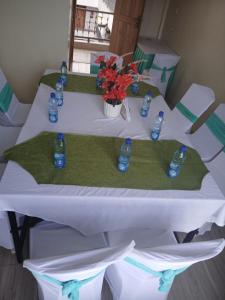 a table with blue bottles and flowers on it at Miriam Inn, Chaka in Nyeri