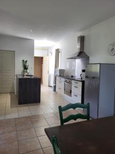 a kitchen with a refrigerator and a table in it at La Ginelle - Appartement Bocage in Airoux +15 photos