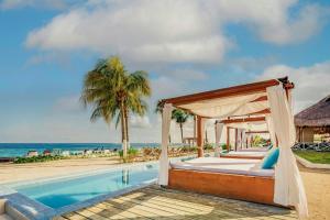 a bed next to a swimming pool next to the beach at The Explorean Cozumel All Inclusive in Cozumel