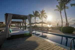 a resort pool with a bed and a view of the ocean at The Explorean Cozumel All Inclusive in Cozumel
