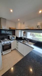 a kitchen with white appliances and a large window at Carilo - semipiso 3 ambientes 1ºpiso in Carilo