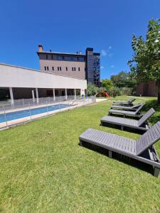a row of benches sitting in the grass near a building at Carilo - semipiso 3 ambientes 1ºpiso in Carilo
