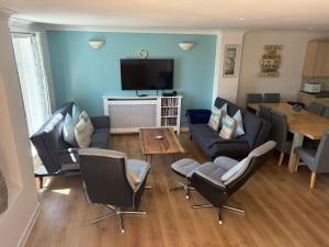 a living room with a couch and chairs and a tv at Seashells in Newquay