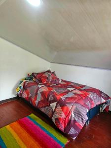 a bed with a colorful comforter in a room at Aguadulce Climbing House in Choachí