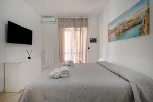 a white bedroom with a bed and a television at Levante Eight Sea View Apartment in Bari