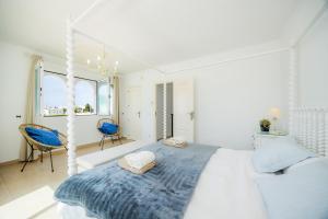 a white bedroom with a bed with a blue blanket at Villa Sa Caleta de Cala D'or in Santanyi +33 photos