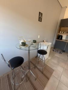 a glass table and two stools in a kitchen at Amazon Loft 09 in Sorriso