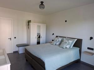 a bedroom with a large bed with white walls at Driemaster, Stijlvol appartement met uitzicht op jachthaven en privé parking, centrum Oostende in Ostend