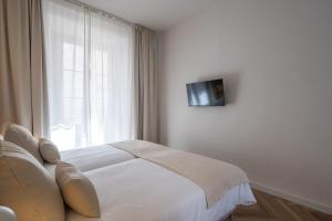 a white bedroom with a bed and a window at Casa Palacio Taubin in Granada