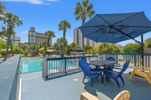 a table and chairs with an umbrella next to a pool at Sun Fun in Myrtle Beach