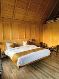 a large bed in a room with wooden walls at The Corbett Lads in Tota Ām