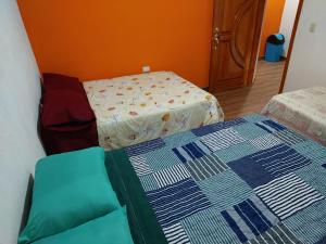 two beds in a room with an orange wall at Hostal Las Armonías 3 in Panajachel
